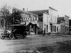 old black and white image of a car next to the garage